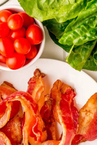 A photo of bacon, tomatoes and lettuce on a white background