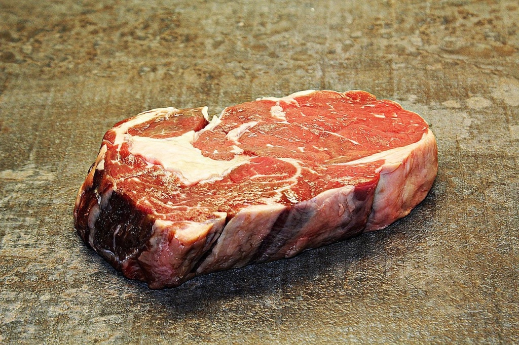 A photo of a raw ribeye steak on a mottled background