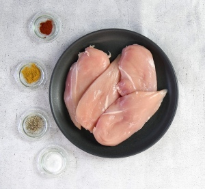 A photo of raw chicken breast on a black plate
