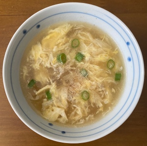 A bowl of egg drop soup on a wooden table 