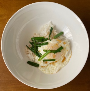 A photo of eggs with soy sauce scallions and rice in a bowl