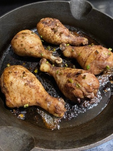 A photo of roasted chickens legs in a cast iron pan.