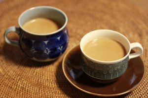 Two mugs filled with chai on a table. 