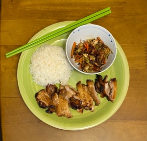A green plate with char siu chicken, rice and eggroll sauté 