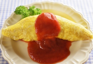Omurice with a splash of ketchup on a plate. 