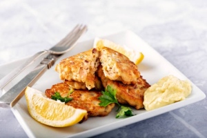 A plate piled with salmon cakes and lemon wedges