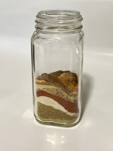 A jar containing layers of different colored spices