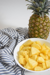 A whole pineapple and cut pineapple on a table
