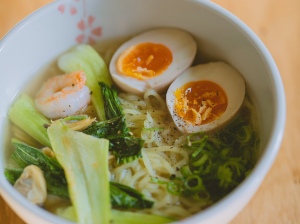 A bowl of noodle soup with shrimp, boiled eggs, bok choy and scallions. 
