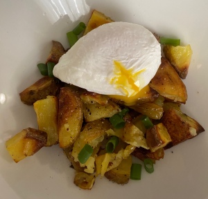 A poached egg sitting on top of home fries. 